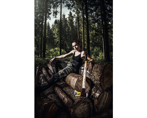 Vrouw zit op stapel hout met bijl in bos