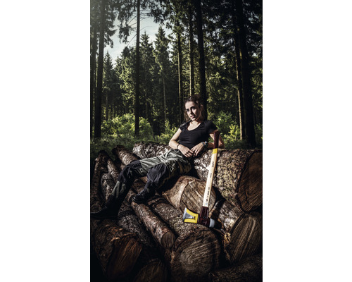 Vrouw zit op boomstammen met een kloofbijl in het bos