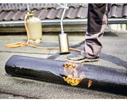 Dakdekker bewerkt dakleer met een brander, gasfles op de achtergrond