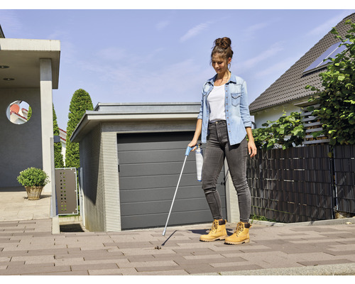 Vrouw gebruikt een afvalgrijper voor een huis met garage