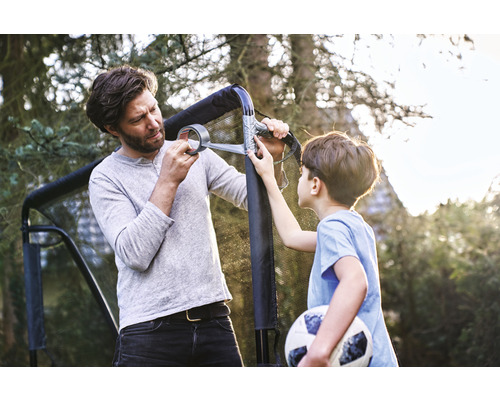 Vader en zoon repareren een voetbaldoel met tape in de tuin.