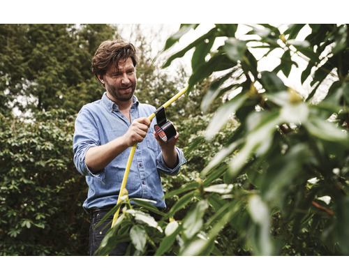 Man repareert gele slang in de tuin met isolatietape