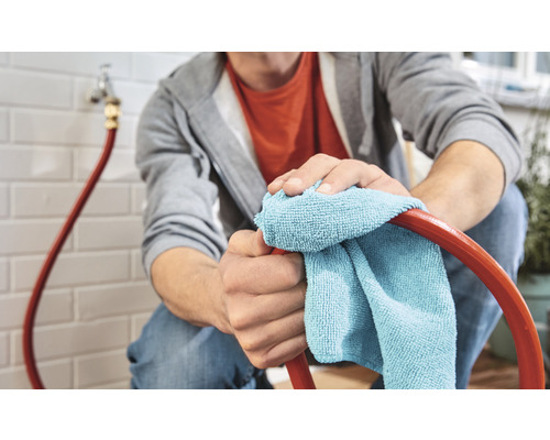 Een persoon maakt een slang schoon met een doek in een huis.