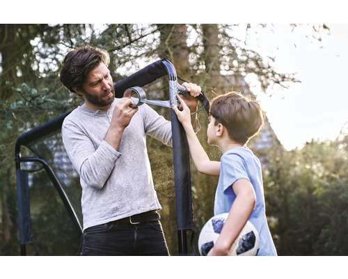 Een vader en zijn zoon repareren een voetbaldoel met ducttape in de tuin.