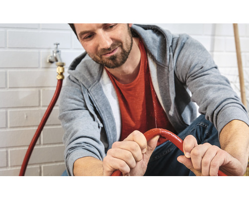 Man repareert een lekkende waterslang in een kamer