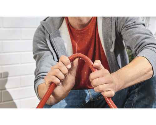 Man houdt een lekkende tuinslang vast