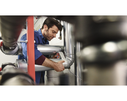 Een man wikkelt een pijp in met afdichtingstape.