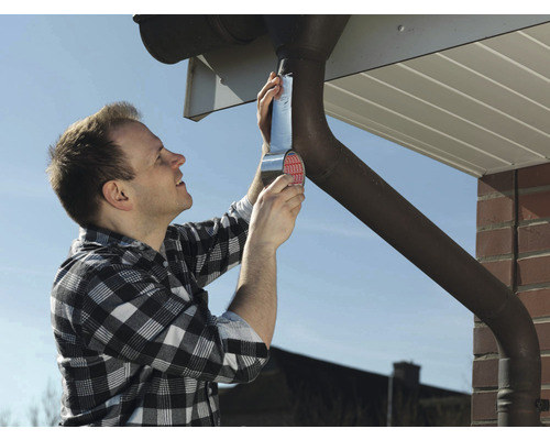 Een man repareert een dakgoot met afdichtband.