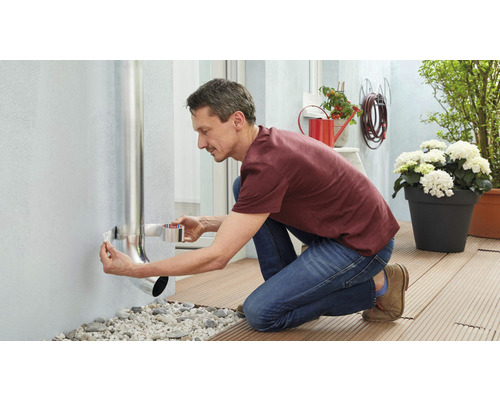 Man bevestigt een regenpijp met afdichtband aan een muur.