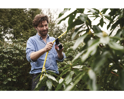 Man repareert een gele slang met ducttape in de tuin.
