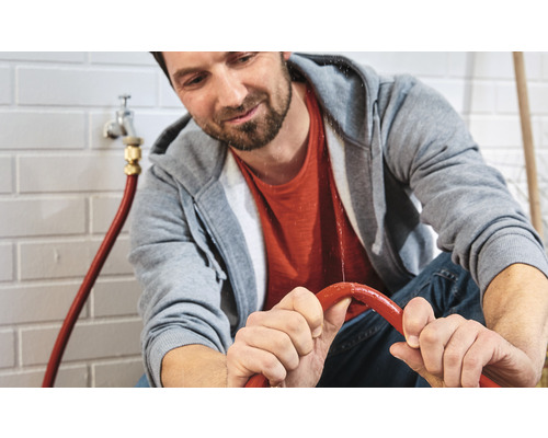 Man houdt een lekkende waterslang vast