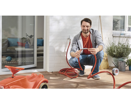 Man verbindt tuinslang op terras met speelgoedauto voor kinderen.