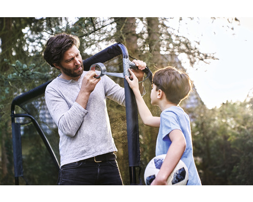 Vader en zoon repareren een voetbaldoel met tape in de tuin.