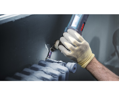 Vakman gebruikt multifunctioneel gereedschap op radiator