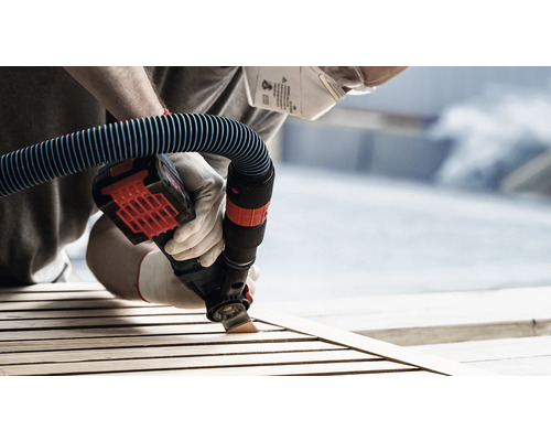 Persoon schuurt hout met elektrisch gereedschap met stofzuigeraansluiting, veiligheidsmasker en handschoenen