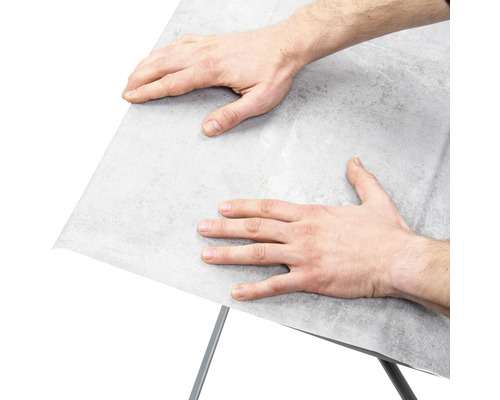 Man bevestigt meubelfolie op een oppervlak.