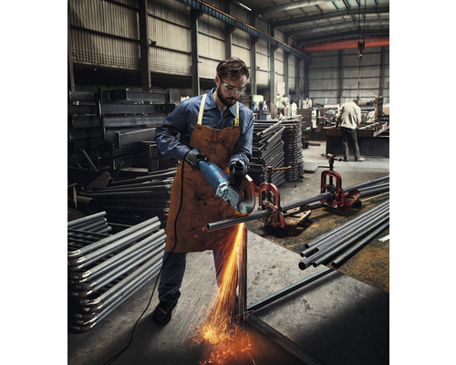 Een arbeider snijdt met een haakse slijper een metalen buis in een werkplaats.