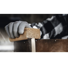Hand met beschermende handschoen schuurt hout met schuurpapier en kurkblok