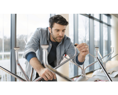 Een man monteert een tafel met metalen poten en vloerbeschermers