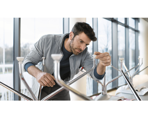 Een man monteert een kapstok met metalen afwerking en witte eindkappen.