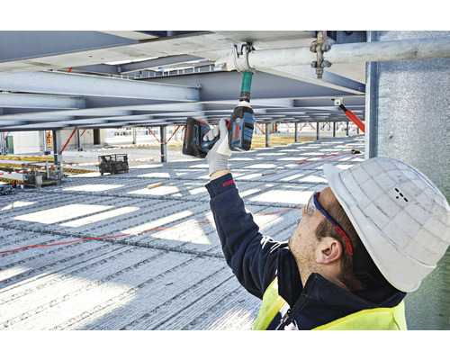 Een bouwvakker gebruikt een accuslagschroevendraaier op een bouwplaats.