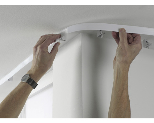 Persoon monteert een gordijnrail aan het plafond