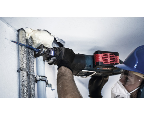 Ambachtsman snijdt een pijp door met een reciprozaag