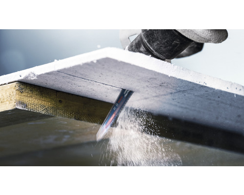 Een decoupeerzaag snijdt een gipsvezelplaat op een houten frame.