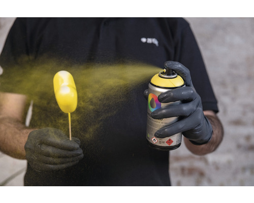 Een persoon spuit een object met een spuitbus.