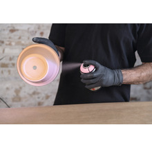 Iemand spuit met een spuitbus verf op een bloempot.