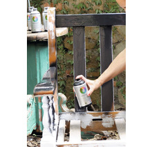 Iemand spuit een houten bank met verfspuitbus