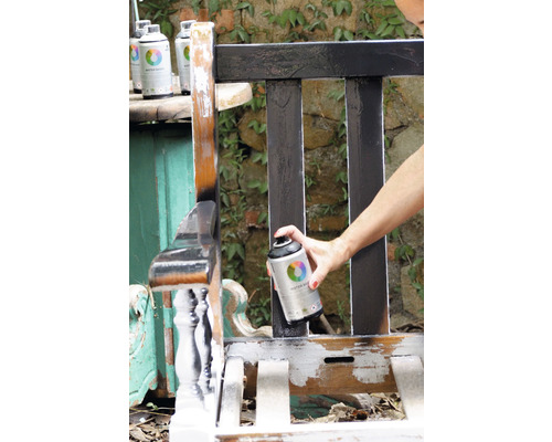 Iemand spuit een houten bank met verfspuitbus