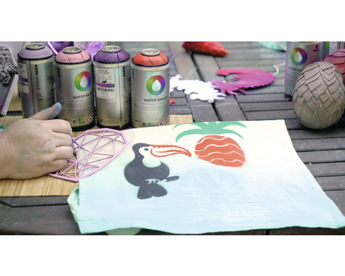 Spuitverf en sjabloon bij het ontwerpen van een stof met tropische motieven