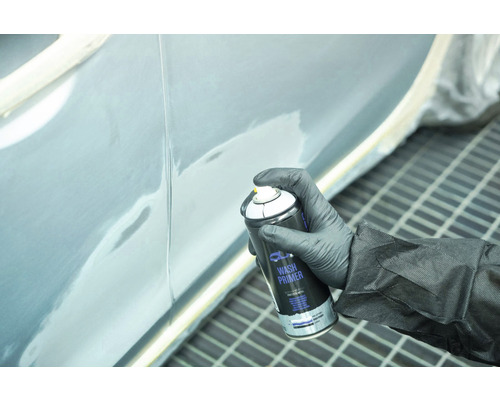 Een persoon die een autodeur grondt met een spuitbus washprimer.