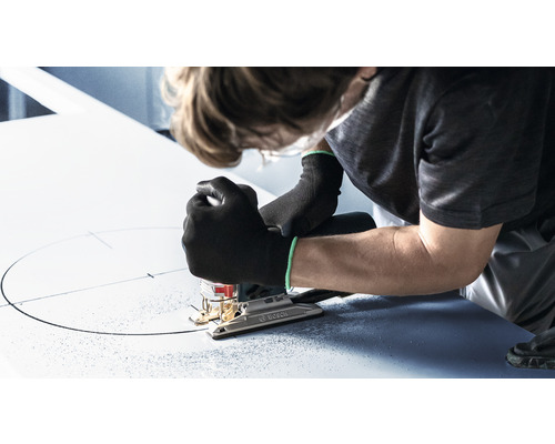 Een persoon zaagt met een decoupeerzaag een cirkel in een plaat.