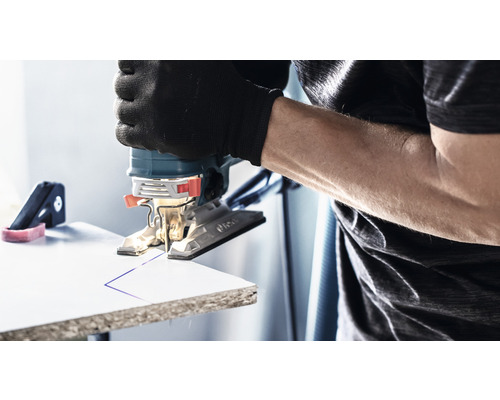 Een decoupeerzaag zaagt een lijn in een werkstuk. De gebruiker draagt handschoenen.