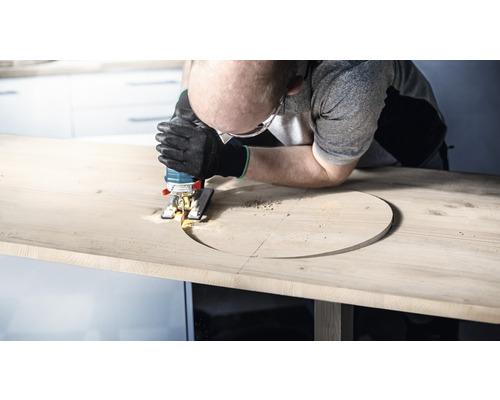 Man zaagt met een decoupeerzaag een gat in een houten plaat.