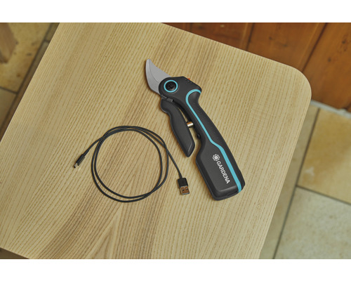 Gardena accu tuinschaar met USB-oplaadkabel op een houten tafel