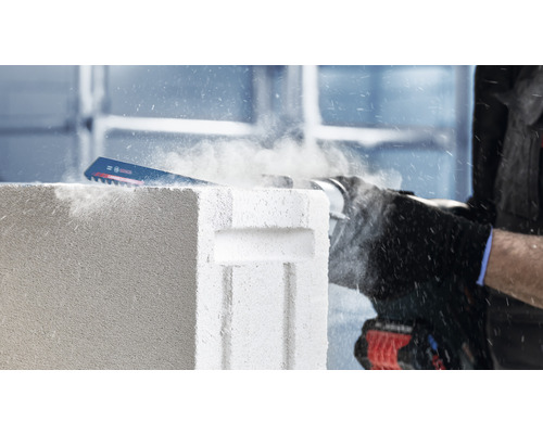 Een reciprozaag snijdt een cellenbetonsteen.