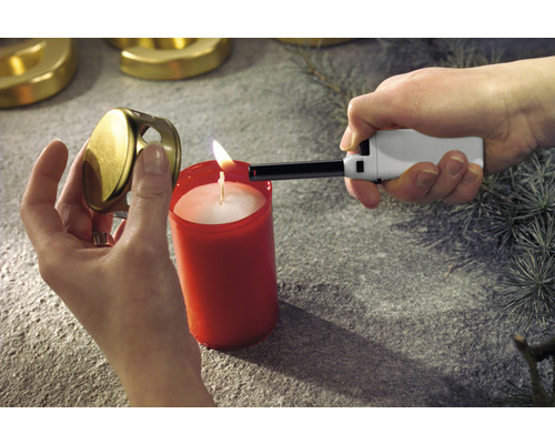 Een persoon steekt met een staafaansteker een kaars aan. Het kaarsdeksel wordt in de hand gehouden.