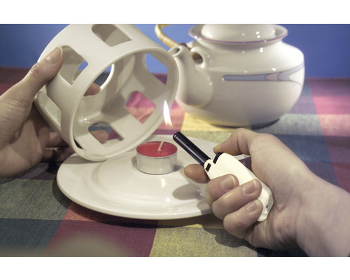 Een theelicht aansteken onder een theelichthouder met een aansteker.