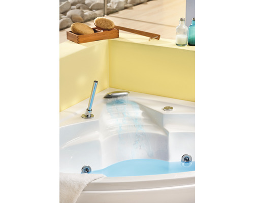 Hoekbad met water, kraan en wellnessaccessoires in de badkamer