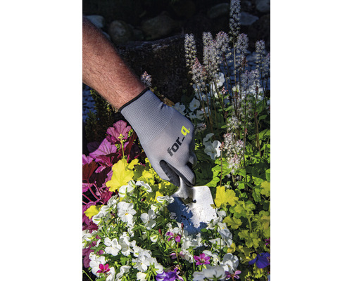 Persoon met tuinhandschoenen en plantschep plant bloemen
