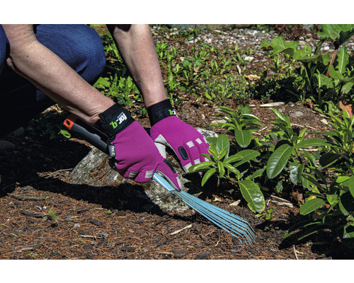 Een persoon harkt tuinafval met een hark, beschermd door tuinhandschoenen.