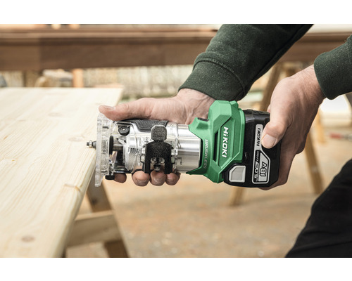 Personen houden een accubovenfrees van HiKoki boven een houten plank.