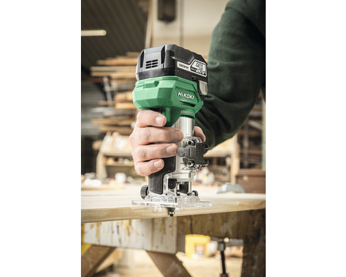 Persoon gebruikt bovenfrees op houten plank. Merk: HiKoki