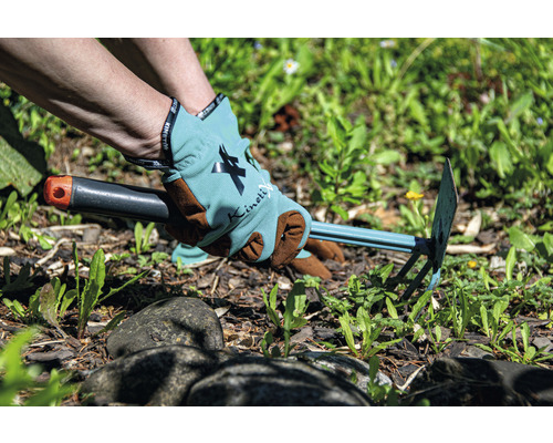 Persoon verwijdert onkruid met een tuinhark en draagt tuinhandschoenen.