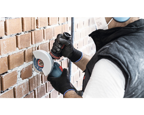 Ambachtsman snijdt een bakstenen muur met een haakse slijper