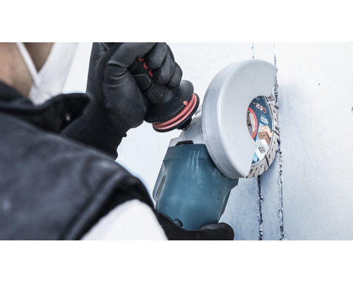 Een persoon gebruikt een haakse slijper op een muur.