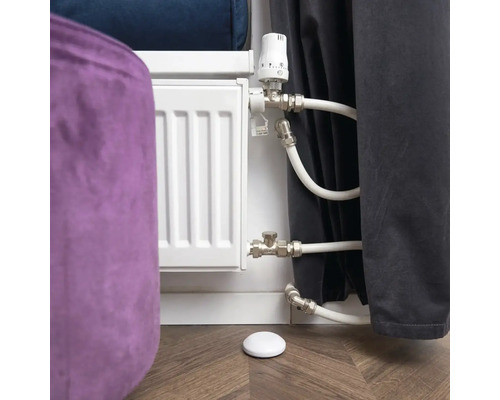 Radiatorknop met radiator en temperatuursensor op houten vloer